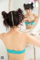 A woman in a blue bikini looking at herself in the mirror.