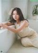 A woman in a white dress sitting on a window sill.