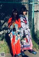 Two young women standing next to each other in front of a fence.