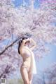 A woman in a pink bikini standing in front of a tree.