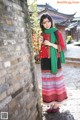 A woman in a red and black dress and green scarf.