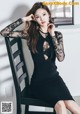 A woman in a black dress sitting on a chair.