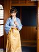 A woman in a blue and yellow kimono standing in front of a door.