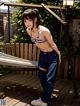 A woman in a bikini top and jeans standing on a wooden deck.