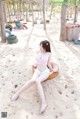 A woman in a pink bikini sitting on a tire in the sand.