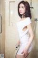 A woman in a white dress standing in a shower.