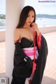 A woman in a black and pink kimono posing for a picture.