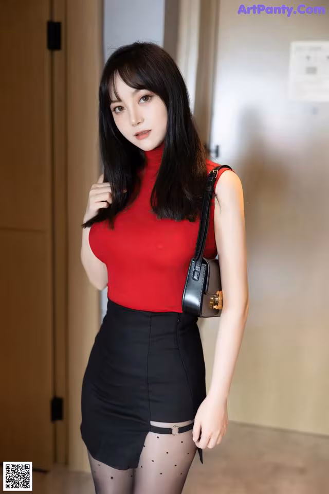 A woman in a red top and black skirt posing for a picture.
