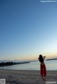 A woman in a red dress standing on a beach.