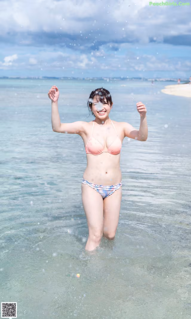 A woman in a bikini standing in the ocean.