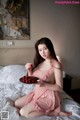 A woman sitting on a bed holding a plate of cherries.