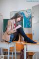 A woman sitting on top of a desk in a classroom.