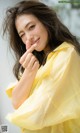 A woman in a yellow shirt posing for a picture.