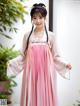 A woman in a pink and white hanbok is posing for a picture.