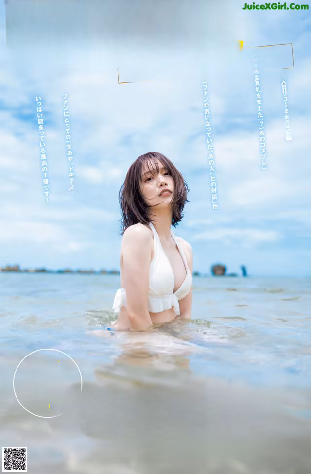A woman in a white bikini standing in the water.