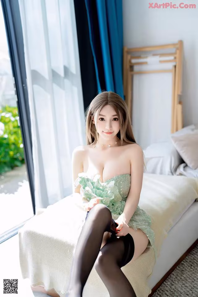 A woman sitting on top of a bed in a green dress.