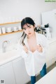 A woman standing in a kitchen next to a sink.