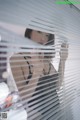 A woman in a black bathing suit looking out of a window.