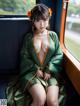 A woman in a green kimono sitting on a train.