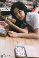 A woman laying on the floor next to a pile of books.