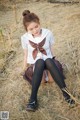 A woman in a school uniform sitting on a hay bale.