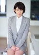 A woman in a gray suit sitting on a white chair.