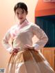 A woman in a white and pink hanbok is posing for a picture.