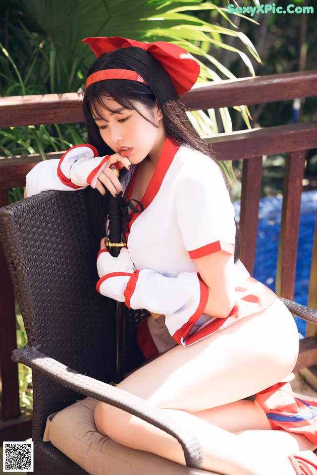 A woman in a red and white outfit sitting on a chair.