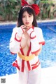 A woman in a red and white outfit posing by a pool.