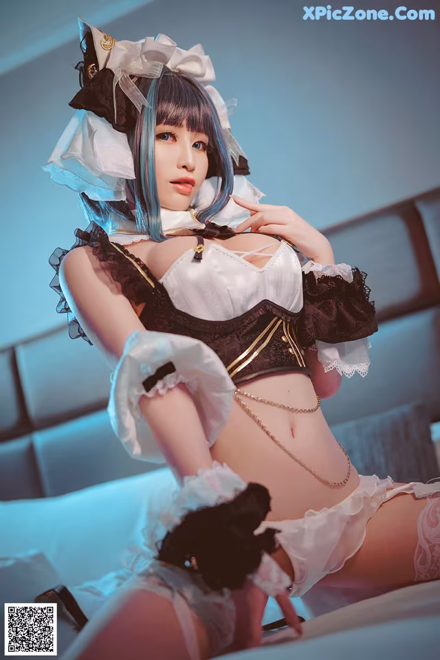 A woman in a maid outfit sitting on a bed.
